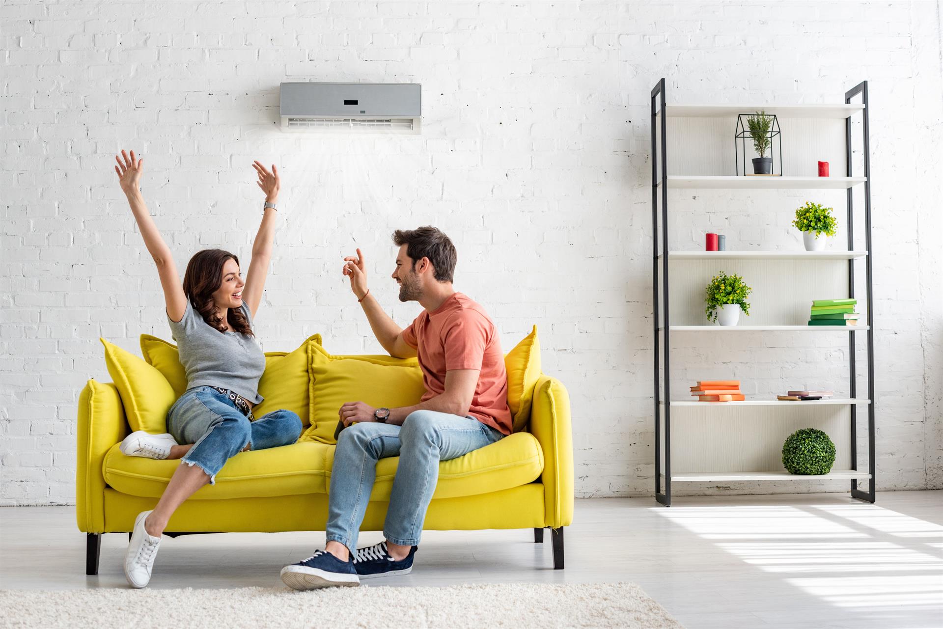 Wohnzimmer mit Klimaanlage an der Wand und Paar auf der Couch