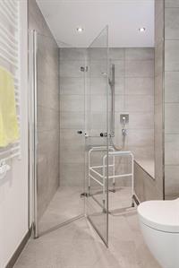 Badezimmer mit barrierefreier Dusche und grauen Fliesen