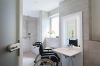 Badezimmer mit herunterfahrbarem Waschbecken und Rollstuhl